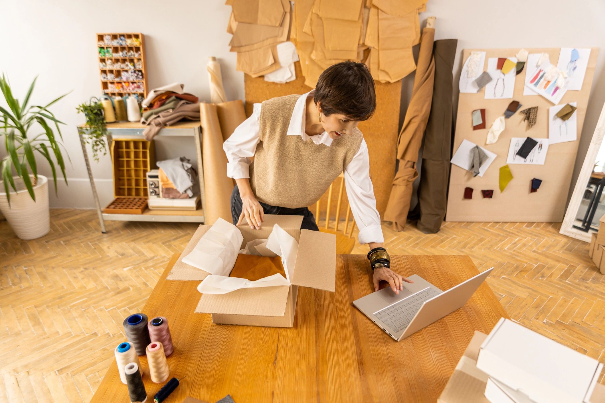 Designer working at a desk with laptop and creative supplies